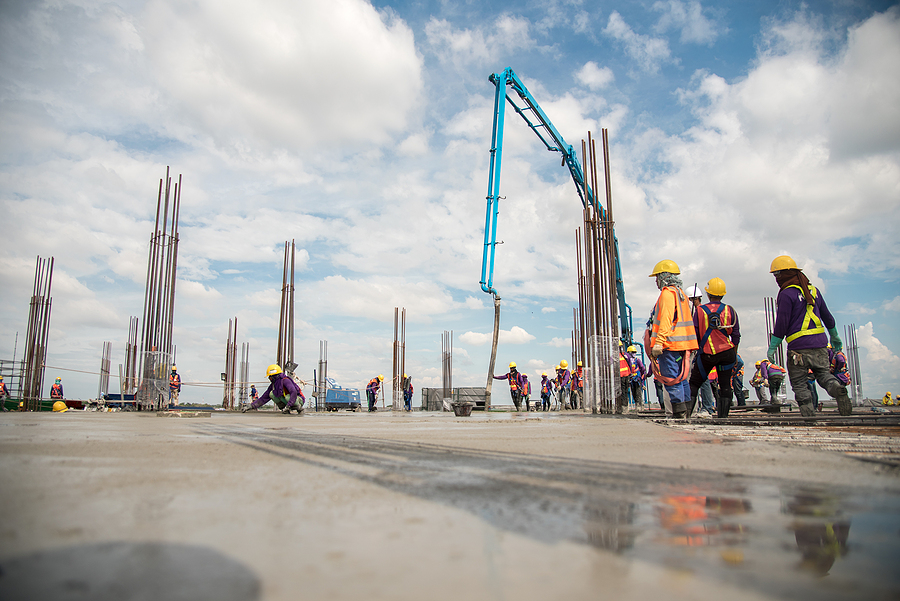 Construction crew pouring concrete on a large commercial site.