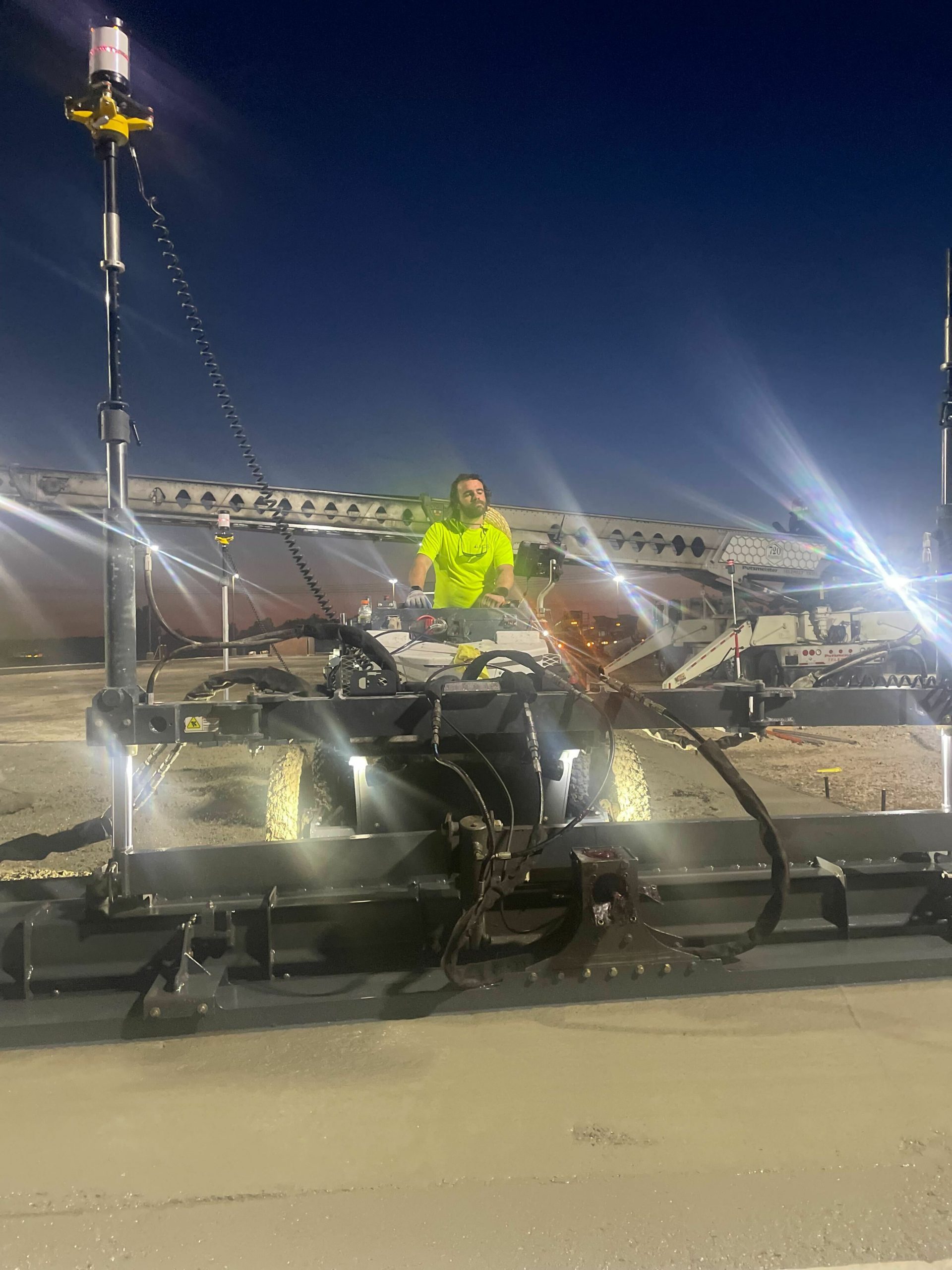 Closeup of a construction worker operating a power screed machine. 