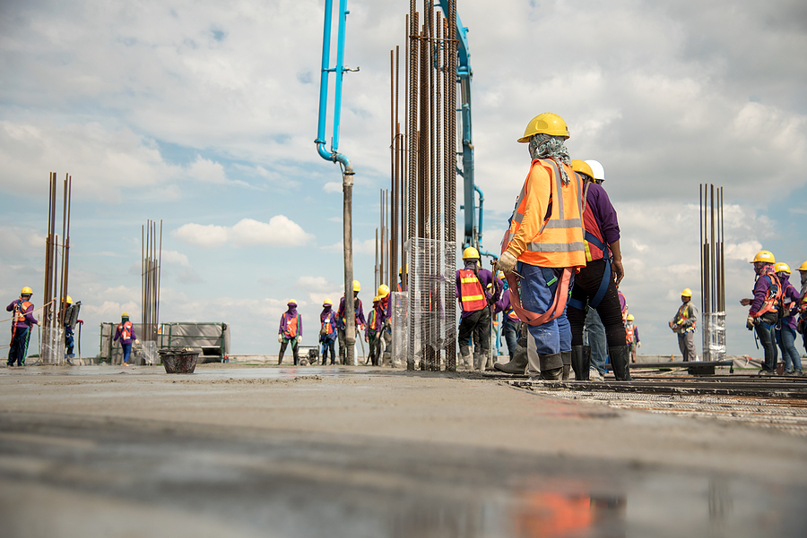 Construction site with concrete workers pouring concrete on a large commercial site. 