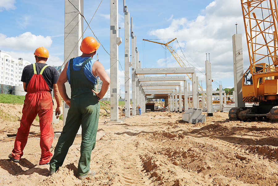Two male construction workers standing on a large commercial construction site where concrete is about to be poured. 
