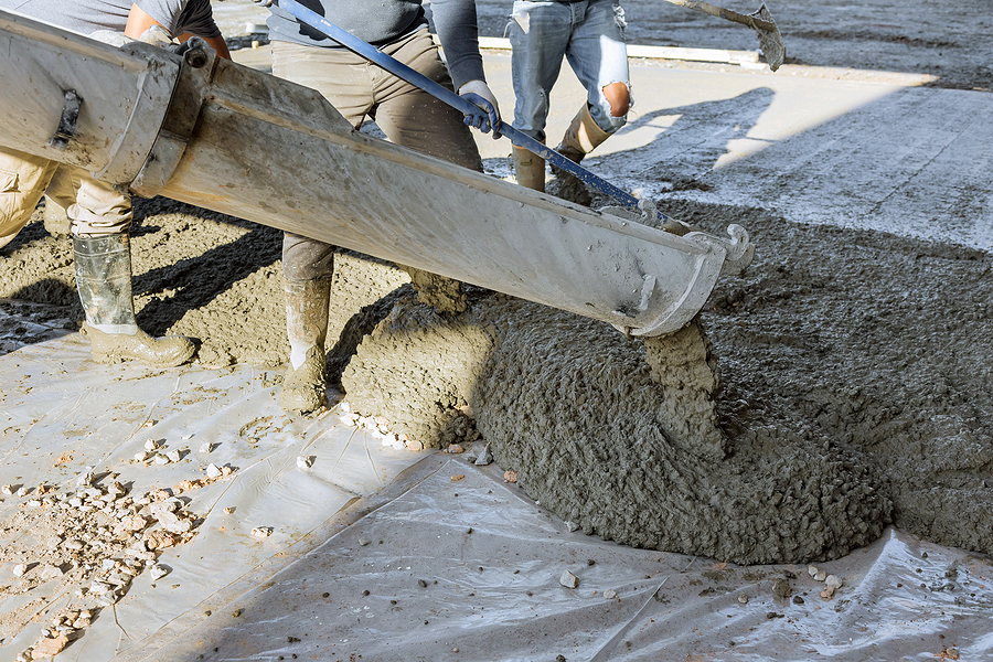 Closeup of workers pouring concrete on a construction site. 