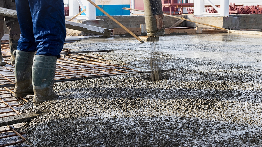 Closeup of a construction worker standing in the middle of an industrial concrete pour. 