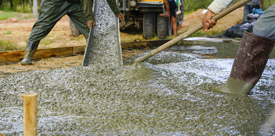 Closeup of concrete workers pouring concrete at a construction site. 