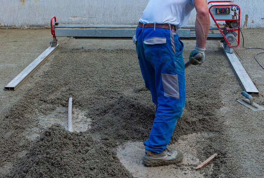 Concrete worker using a laser screed machine to help level the concrete. 